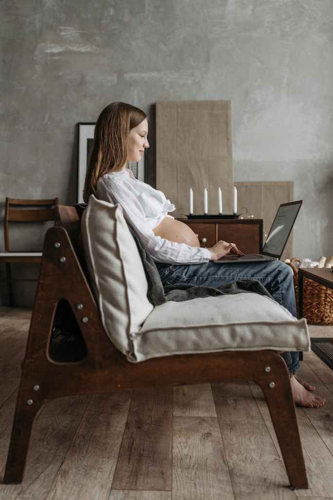 a pregnant woman typing on a laptop